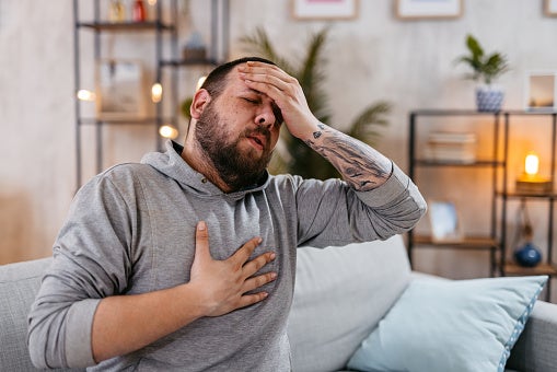 Man suffering from chest pain, holding his forehead, having breathing issues.