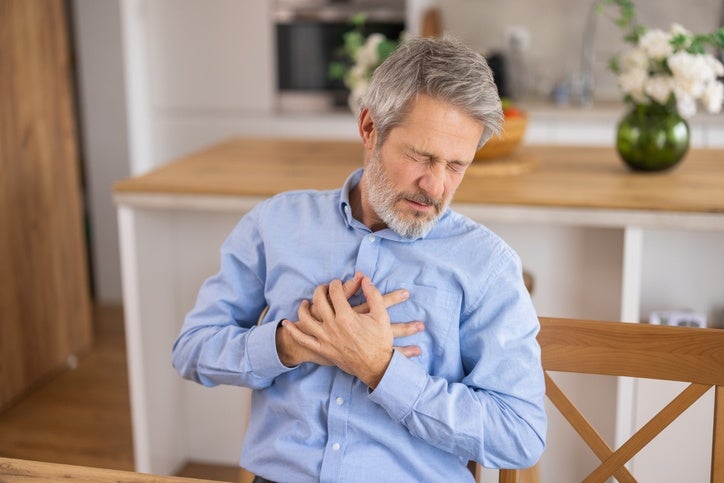 Person clutching chest during heart attack symptoms in Sugar Land, TX